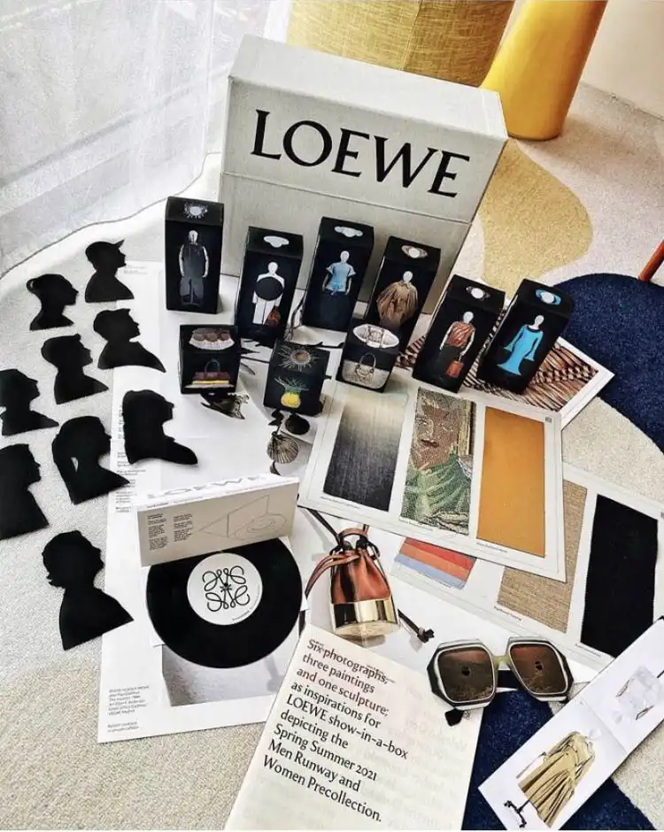 The LOEWE ‘Show in a Box’ archive set styled on a rug, with the team silhouettes, miniature garment boxes, vinyl record and sunglasses